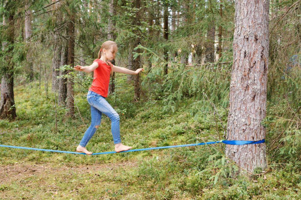 Young Child finding balance on a slackline between two trees