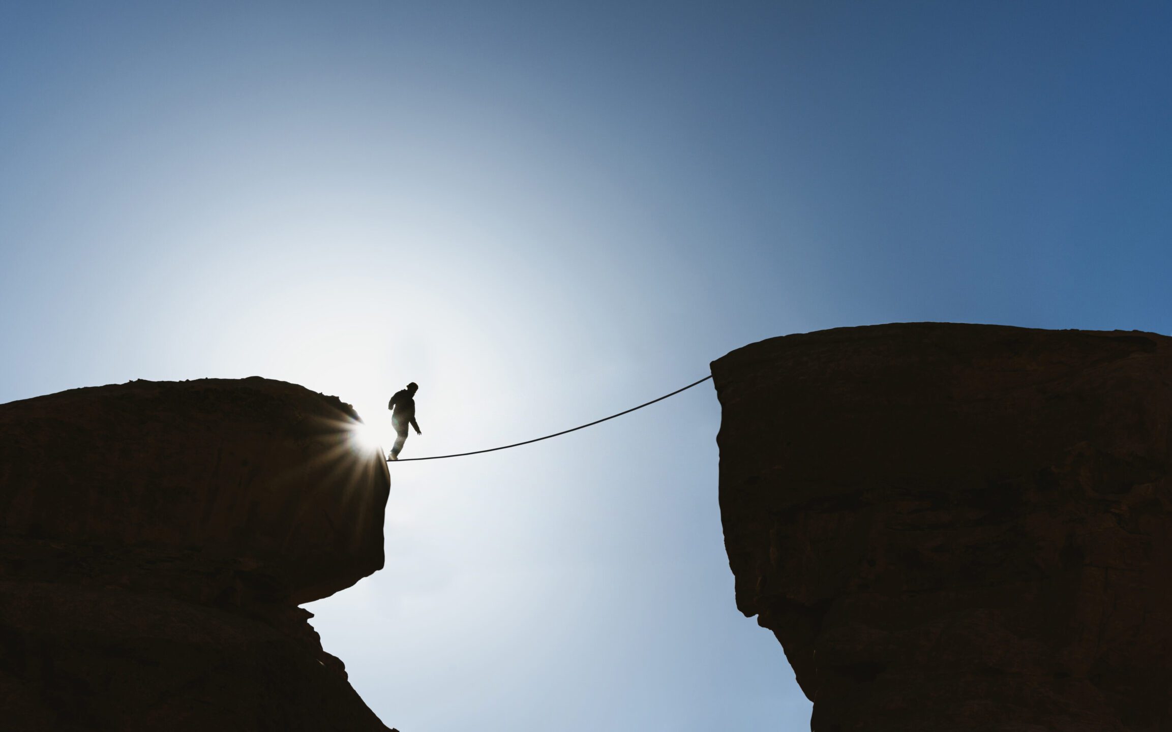 Man on rope high between two cliffs
