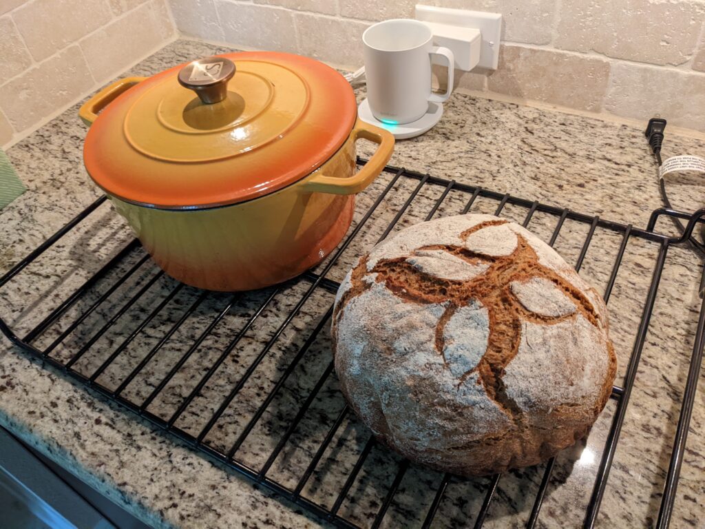 Round loaf of artisan bread and an orange dutch over pan:  baking bread the old fashioned way