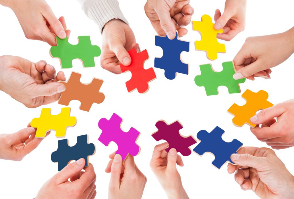 Cropped image of business people holding colorful jigsaw pieces over white background