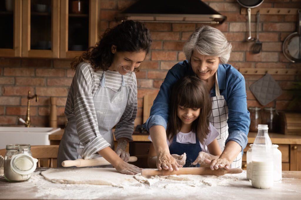 Mom, grandmother and grandchild rolling dough in a pretty kitchen