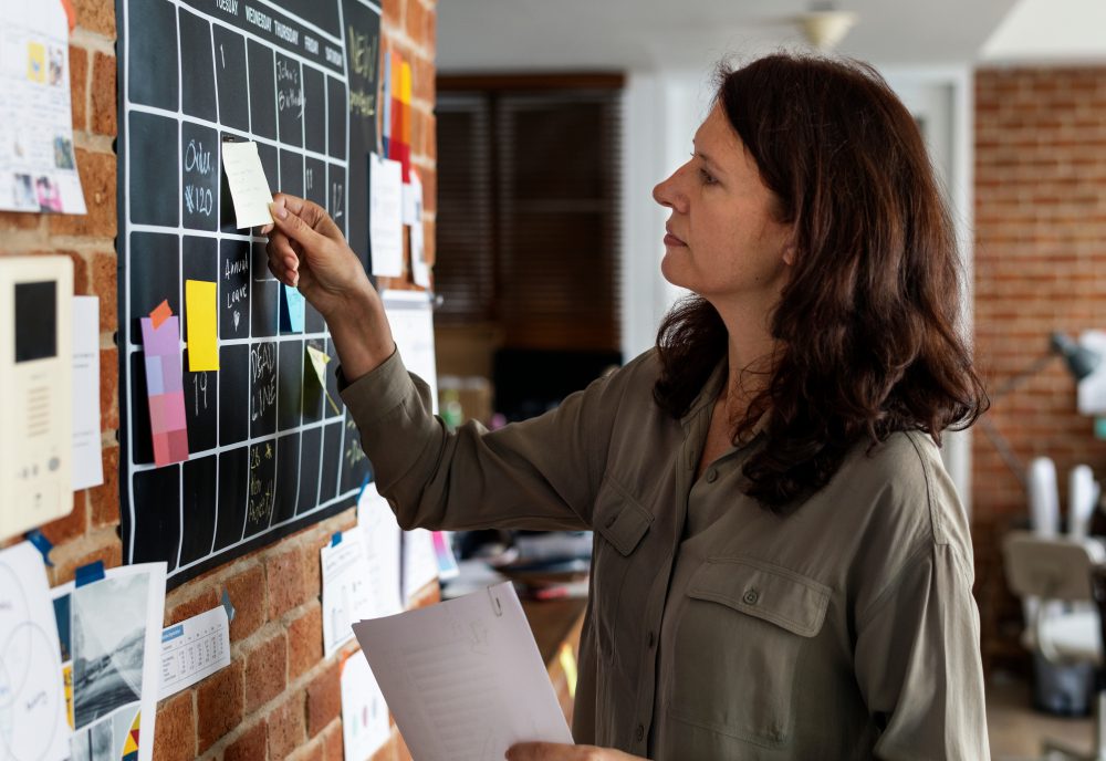 Woman adding notes to her wall calendar - setting priorities are key to a meaningful life